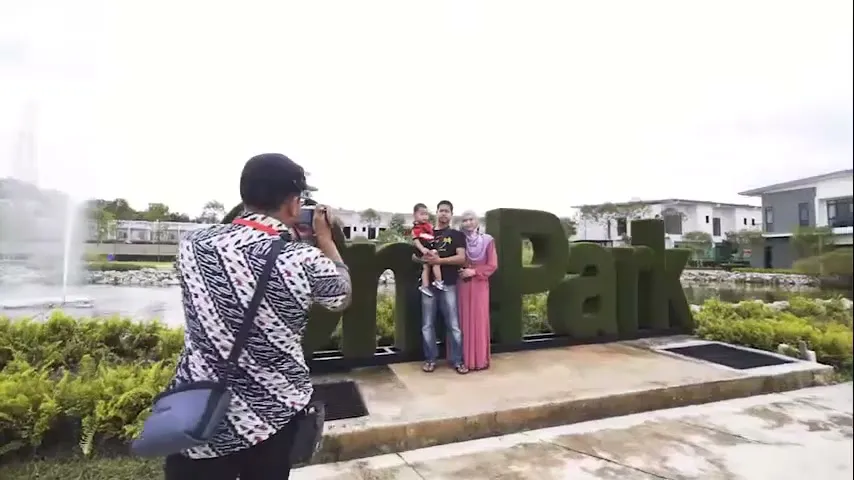 A family posing for a photograph in front of the OnePark sign at the Hari Raya open house